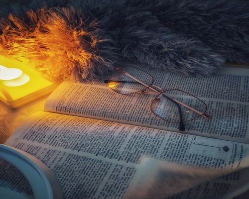 Open book resting on a blanket illuminated by a warm reading lamp at night