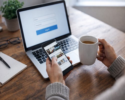 Woman taking a relaxing break holding a cup of tea near her laptop on a wooden desk
